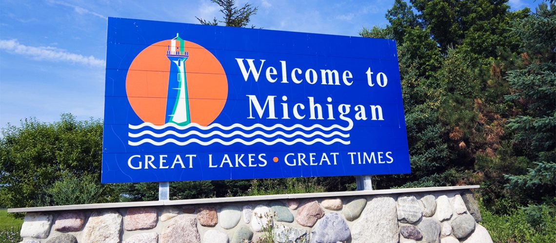 A blue outdoor sign that says "Welcome to Michigan" sits on top of a base made of large rocks